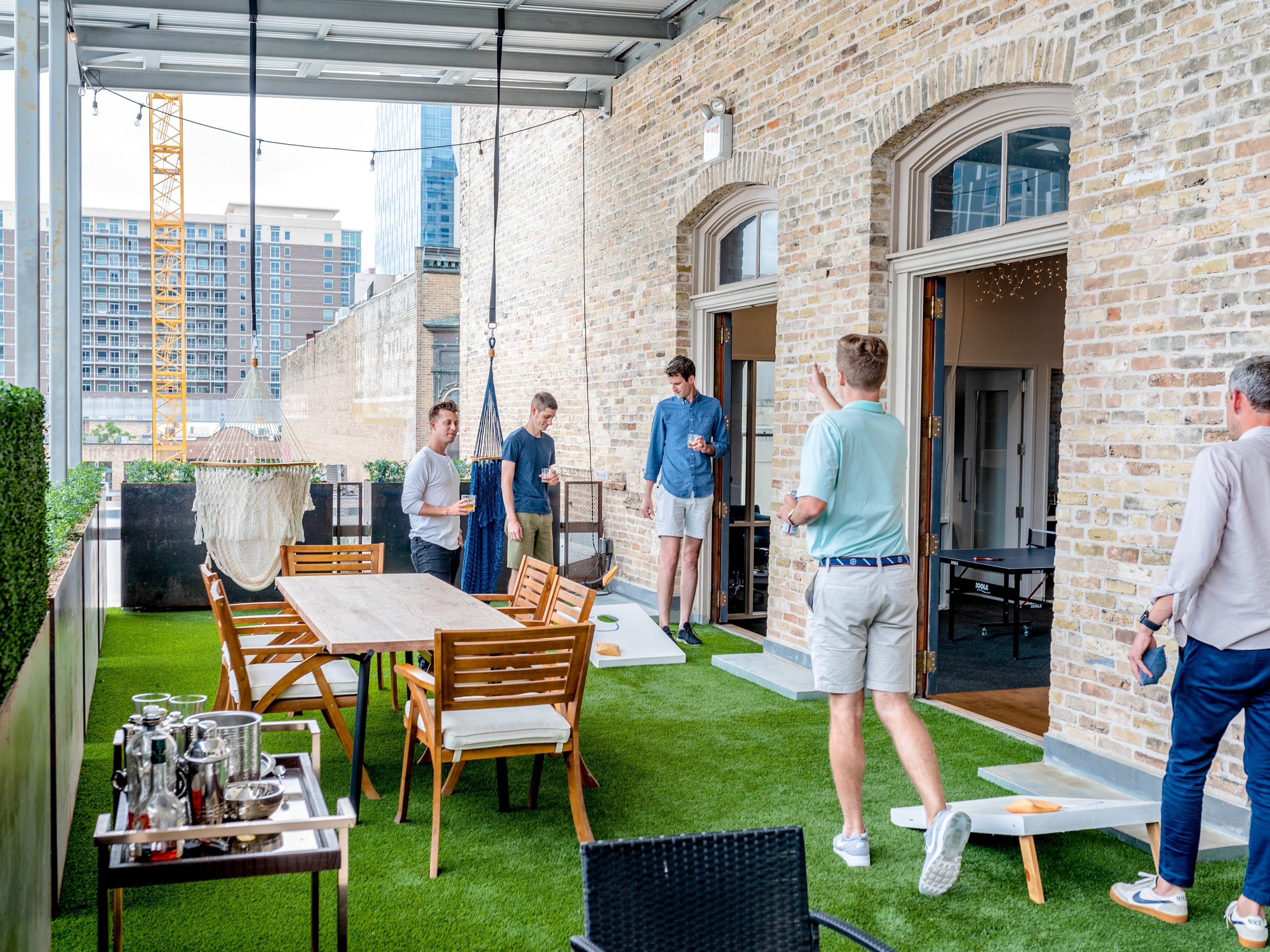 Bunch of preppy dudes playing corn hole outside on a balcony/porch